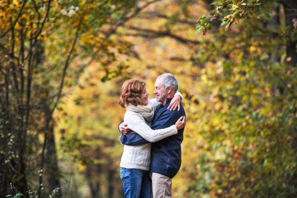 A portrait of an active senior couple standing in an autumn nature. Copy space.