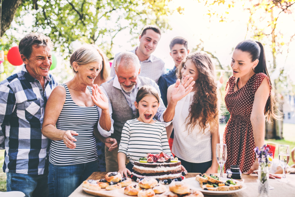 Family celebration outside in the backyard.Big garden party. Birthday party. Small girl with a birthday cake.