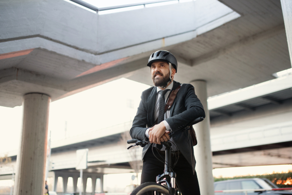 Hipster businessman commuter with electric bicycle traveling home from work in city. Copy space.