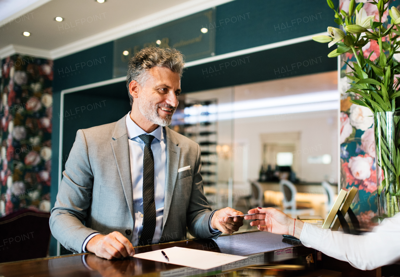 Mature businessman checking in at hotel reception.