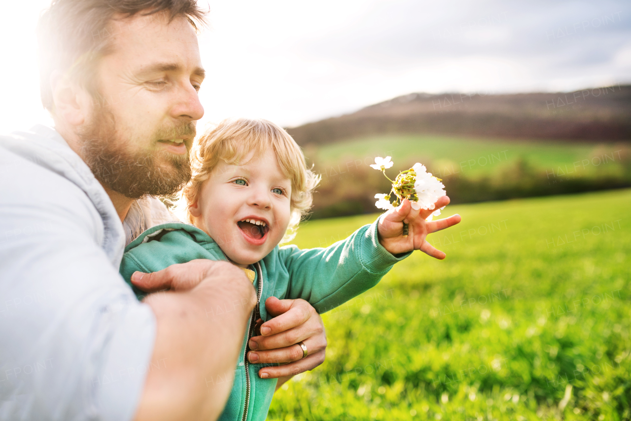 A father with his toddler son outside in green sunny spring nature.