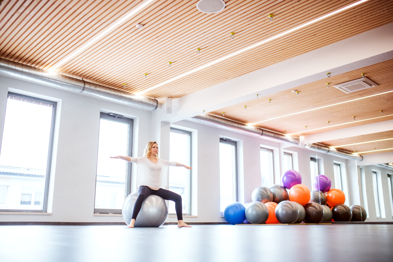 Young beautiful woman doing exercise with a fitball in a gym.