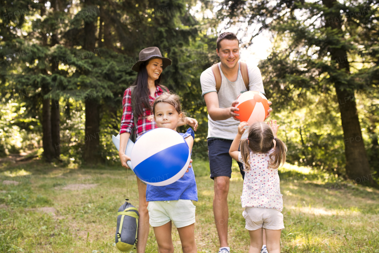 Beautiful young family with cute little daughters going camping in forest.