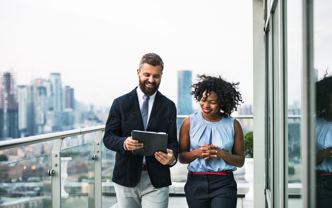 A portrait of businesspeople standing against London rooftop view, discussing something.