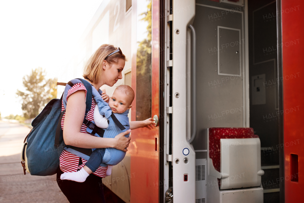 Young mother travelling with baby boy by train. Railway journey of a beautiful woman and her son.