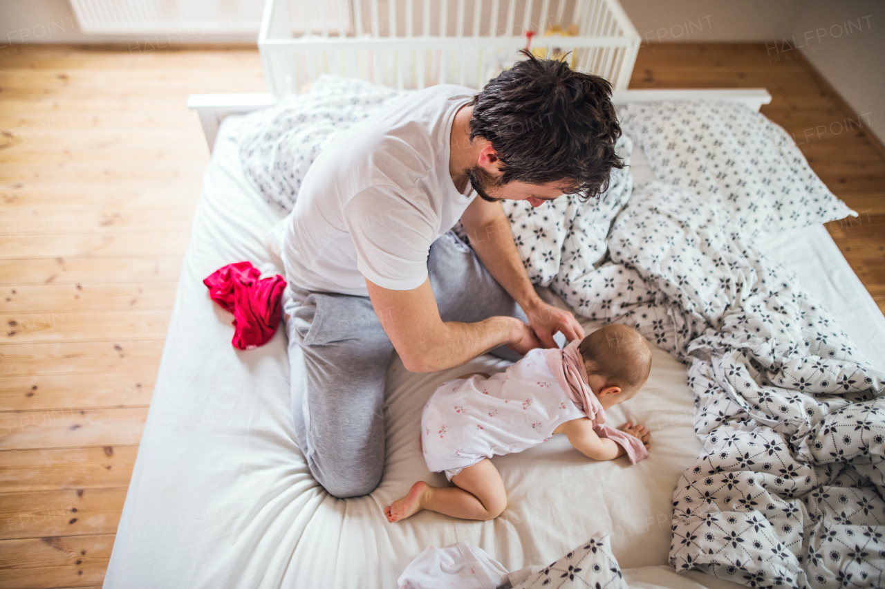 Father with a toddler girl on bed at home at bedtime. Paternity leave.