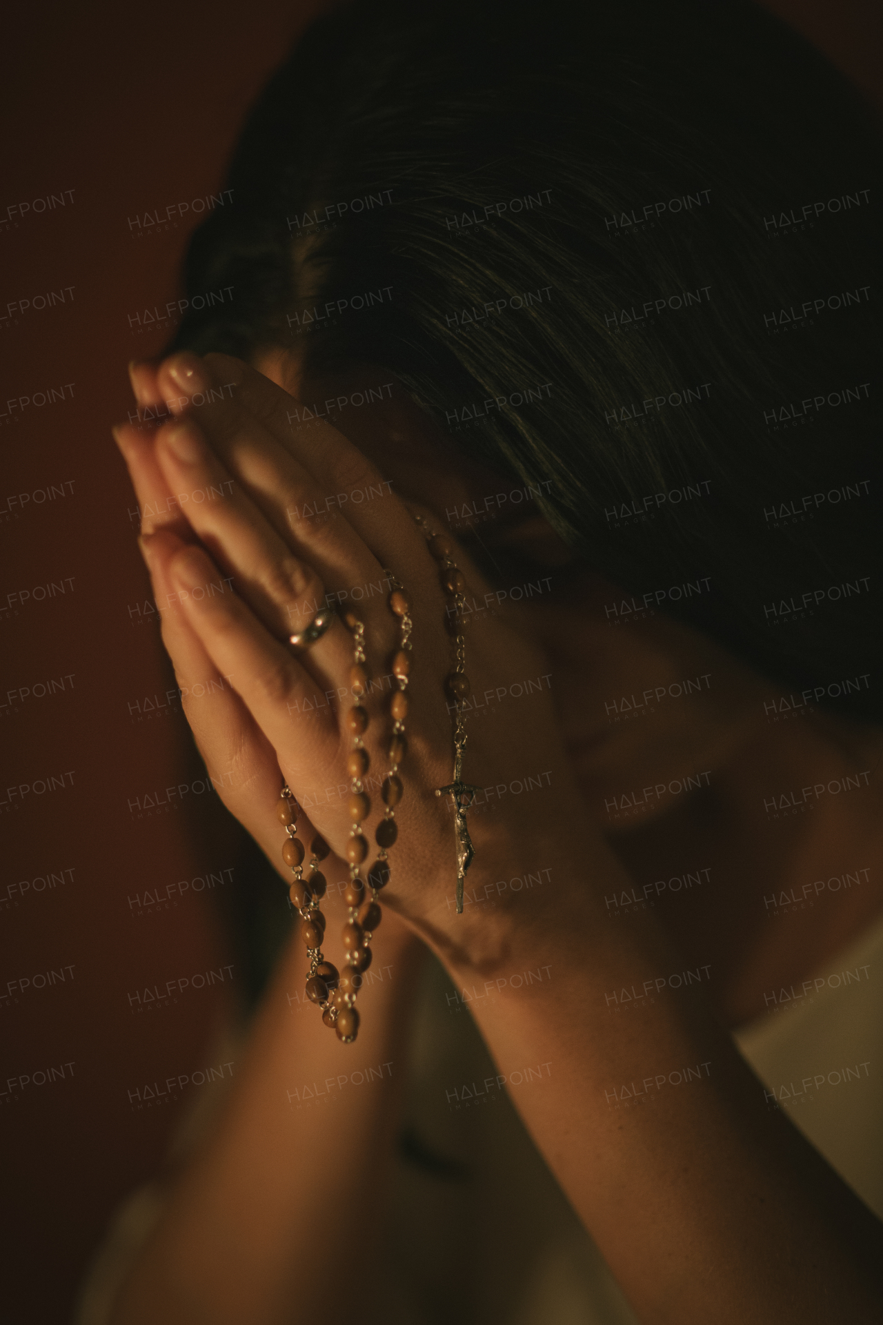 Unrecognizable woman with a rosary praying in the church