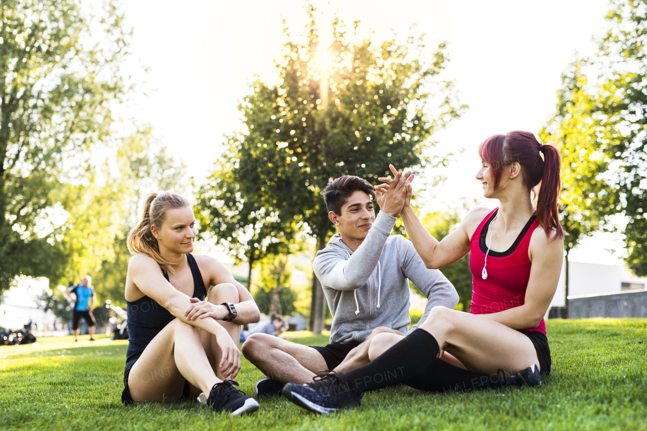 Group of young runners resting in a green sunny park.