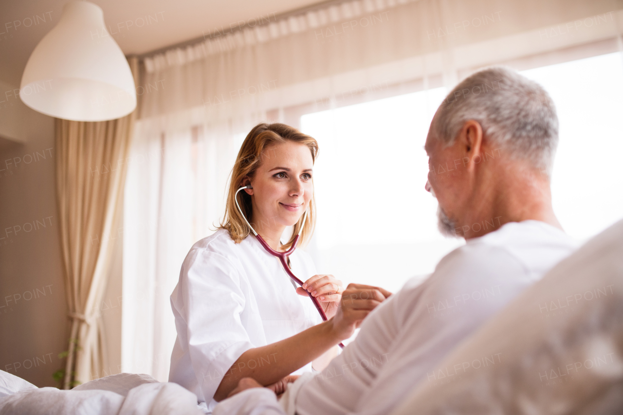 Health visitor and a senior man during home visit. A female nurse or a doctor examining a man.
