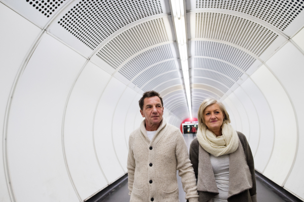 Beautiful senior couple in winter clothes walking in the hallway of subway in Vienna