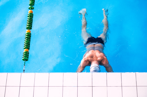 Senior man in an indoor swimming pool. Active pensioner enjoying sport.