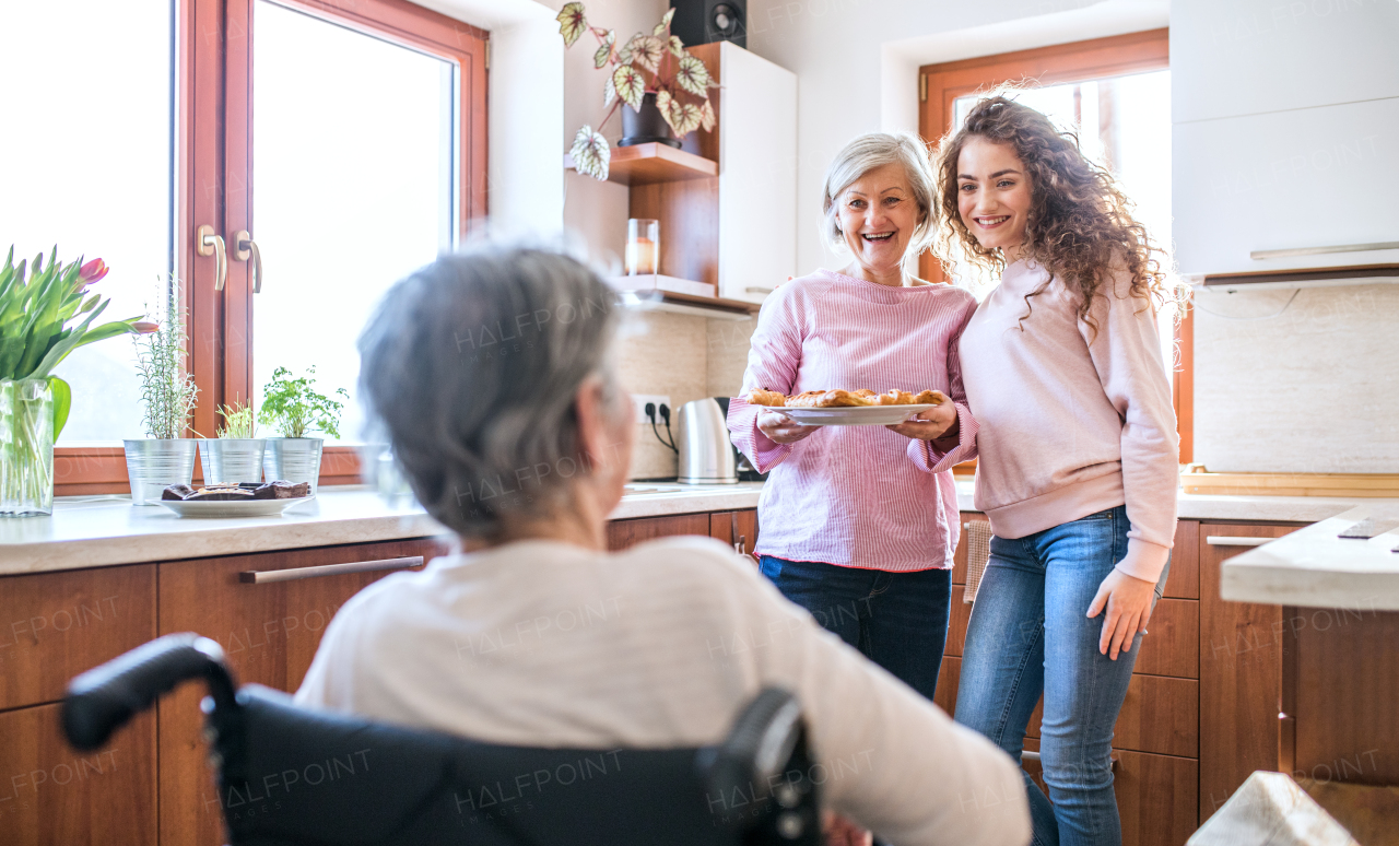 A teenage girl with her mother and grandmother in wheelchair at home. Family and generations concept.