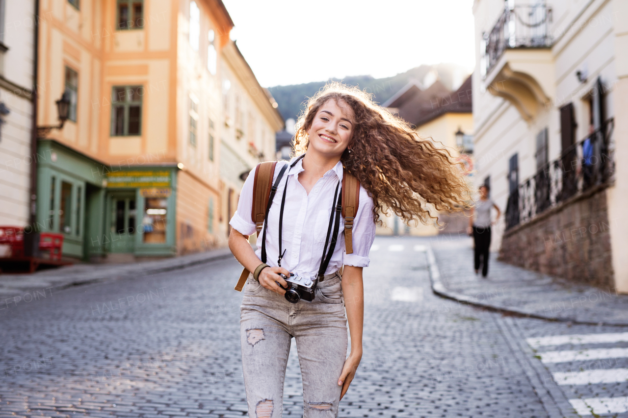 Beautiful young tourist with camera in the old town.