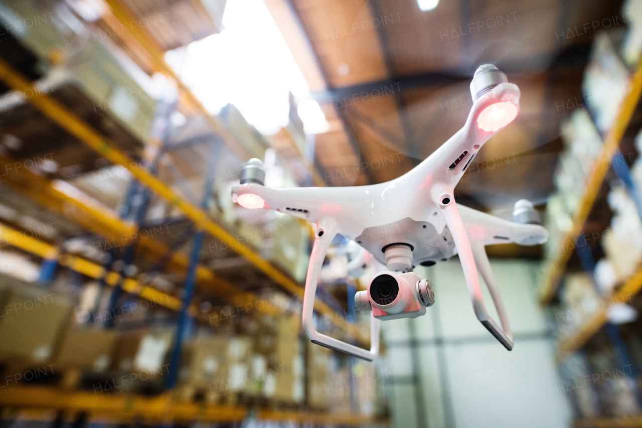 White drone flying inside the warehouse, under a wooden roof.