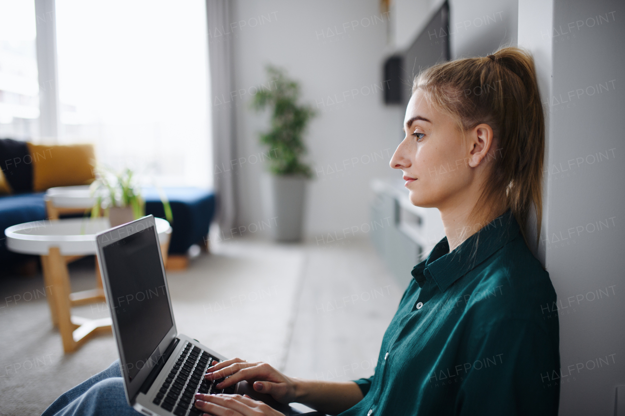 A young woman student with laptop at home, home office and learning.