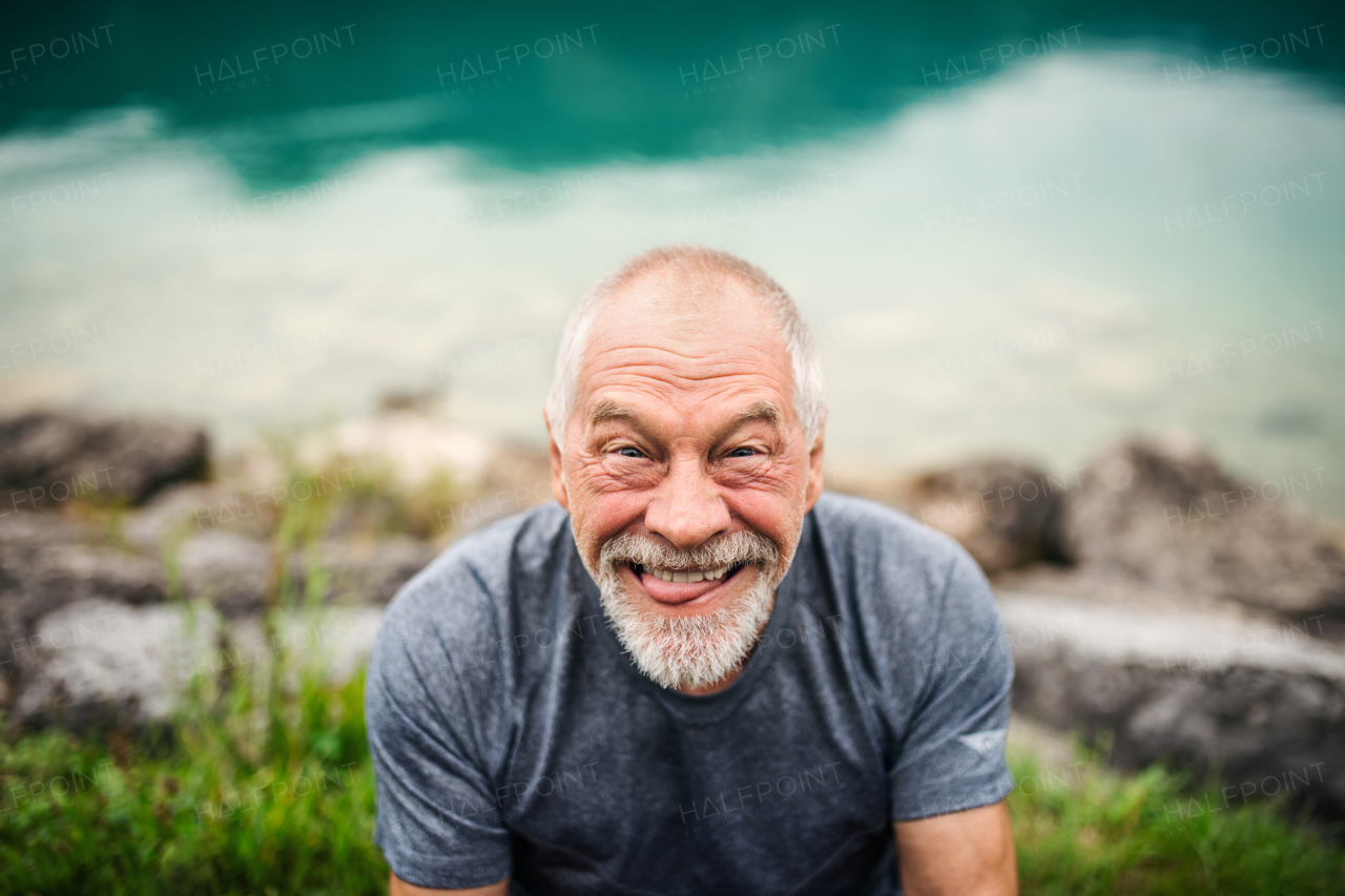 A front view portrait of senior man pensioner standing outdoors in nature, grimacing.