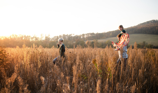 Side view of family with small daughter on a walk in autumn nature, walking.