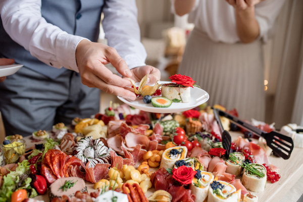 Midsection of a man putting food on a plate on a indoor family birthday party.