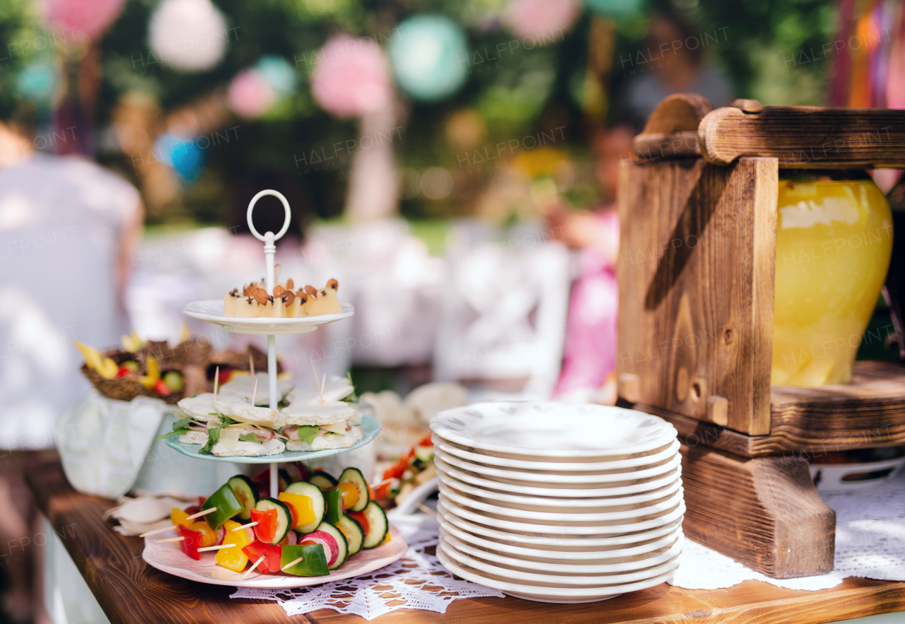 Food on table on kids birthday party outdoors in garden in summer, celebration concept.