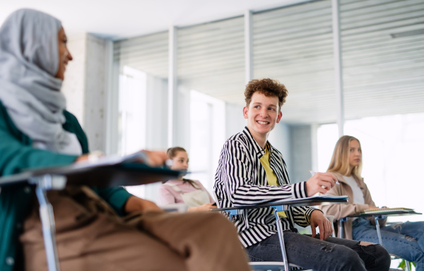 A portrait of university student sitting in classroom indoors, studying.