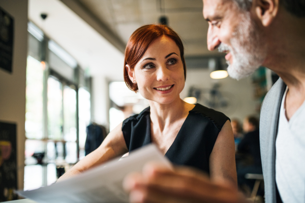 A man and woman with coffee having business meeting in a cafe, discussing issues.