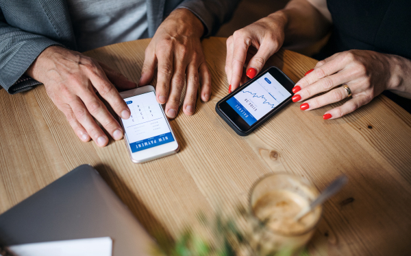 A midsection of businesspeople having business meeting in a cafe, using smartphones.