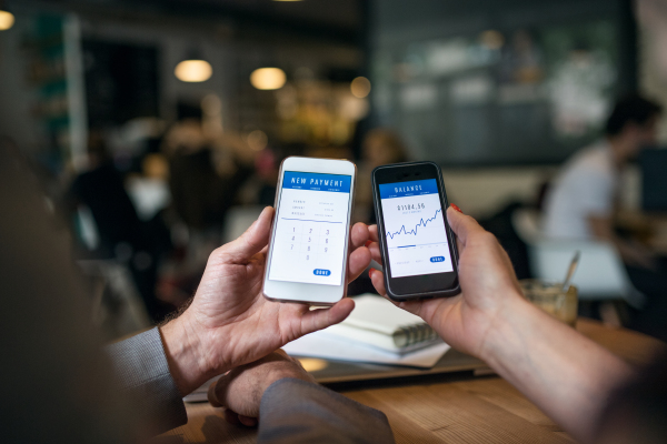A midsection of businesspeople having business meeting in a cafe, using smartphones.