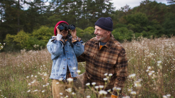 Senior man with his little grandson resting at autumn meadow during camping.