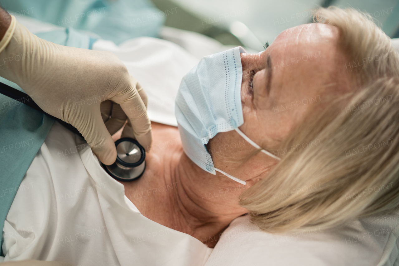 Unrecognizable doctor and covid-19 infected patient in bed in hospital, coronavirus concept.