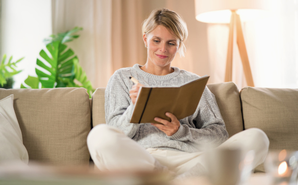 Front view portrait of woman relaxing indoors at home, mental health care concept.