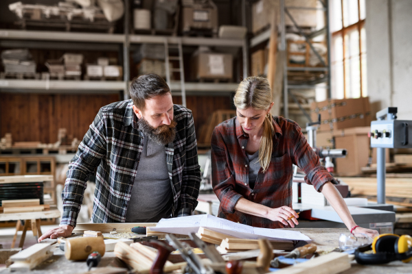 Two carpenters a man and a woman talking about design of products. Small business concept.