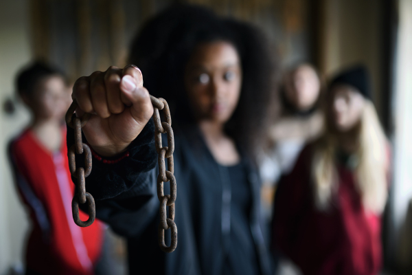Portrait of mixed-race teenager girl with chain indoors in abandoned building. Focus on foreground.