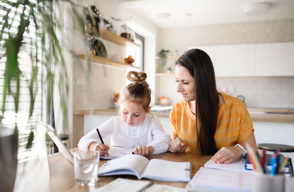 Mother and small daughter learning indoors at home, Corona virus and quarantine concept.