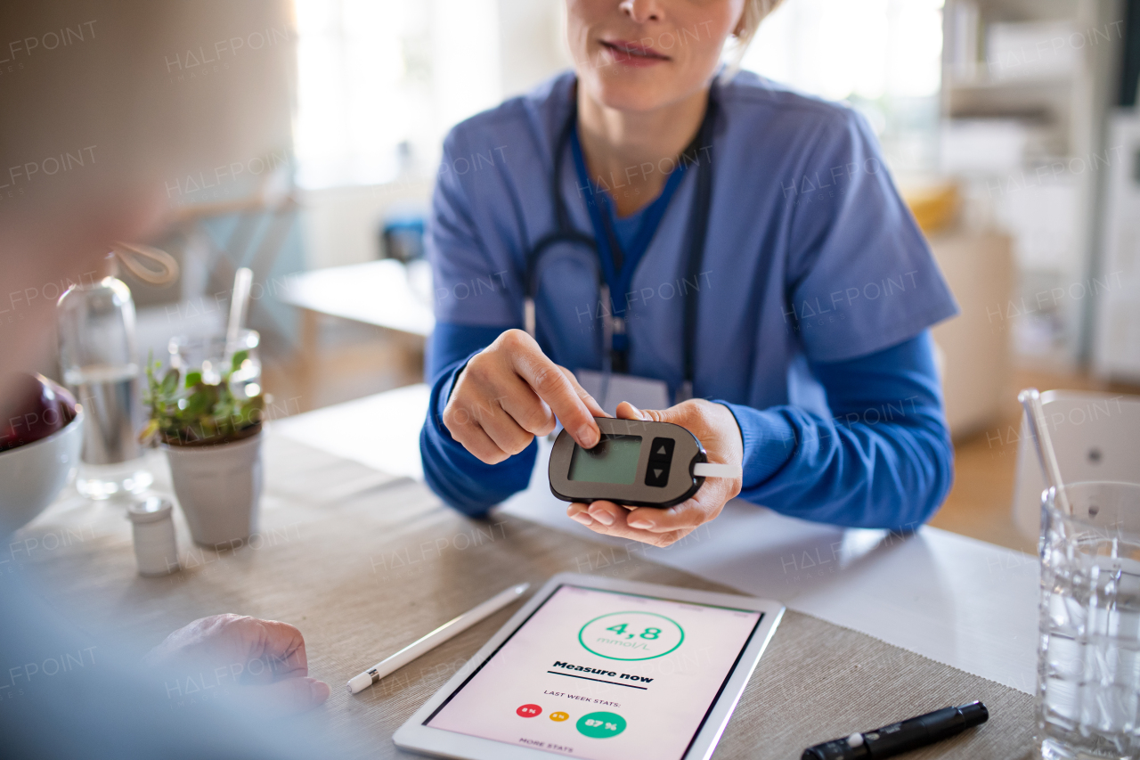 Nurse, caregiver or healthcare worker with senior woman patient, measuring blood glucose indoors.