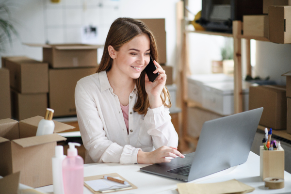 Young woman dropshipper with laptop working at home, processing orders. Coronavirus concept.