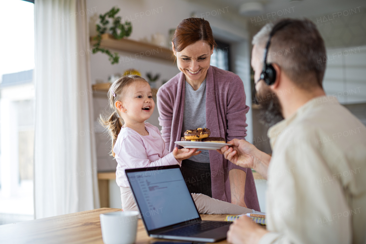 A family with small daughter indoors at home, everyday life and home office with child concept.