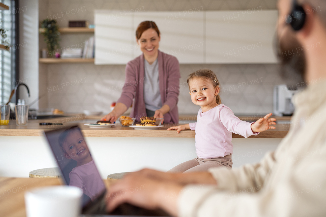 A family with small daughter indoors at home, everyday life and home office with child concept.
