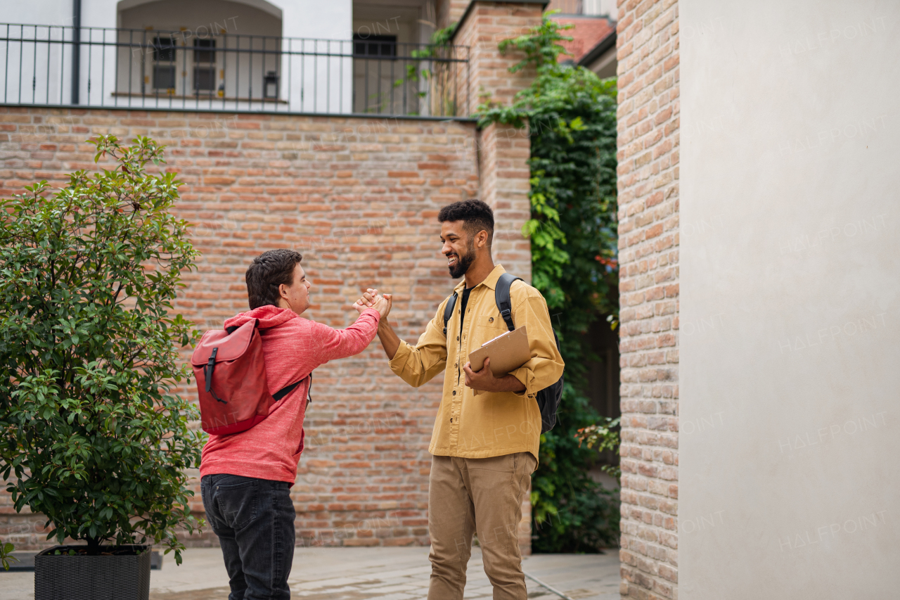 A young man with Down syndrome and his mentoring friend meeting and greeting outdoors
