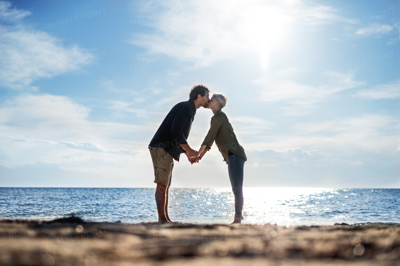 A young couple standing outdoors on beach, kissing. Copy space.