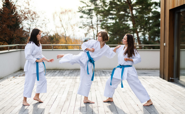 A group of young women practising karate outdoors on terrace.