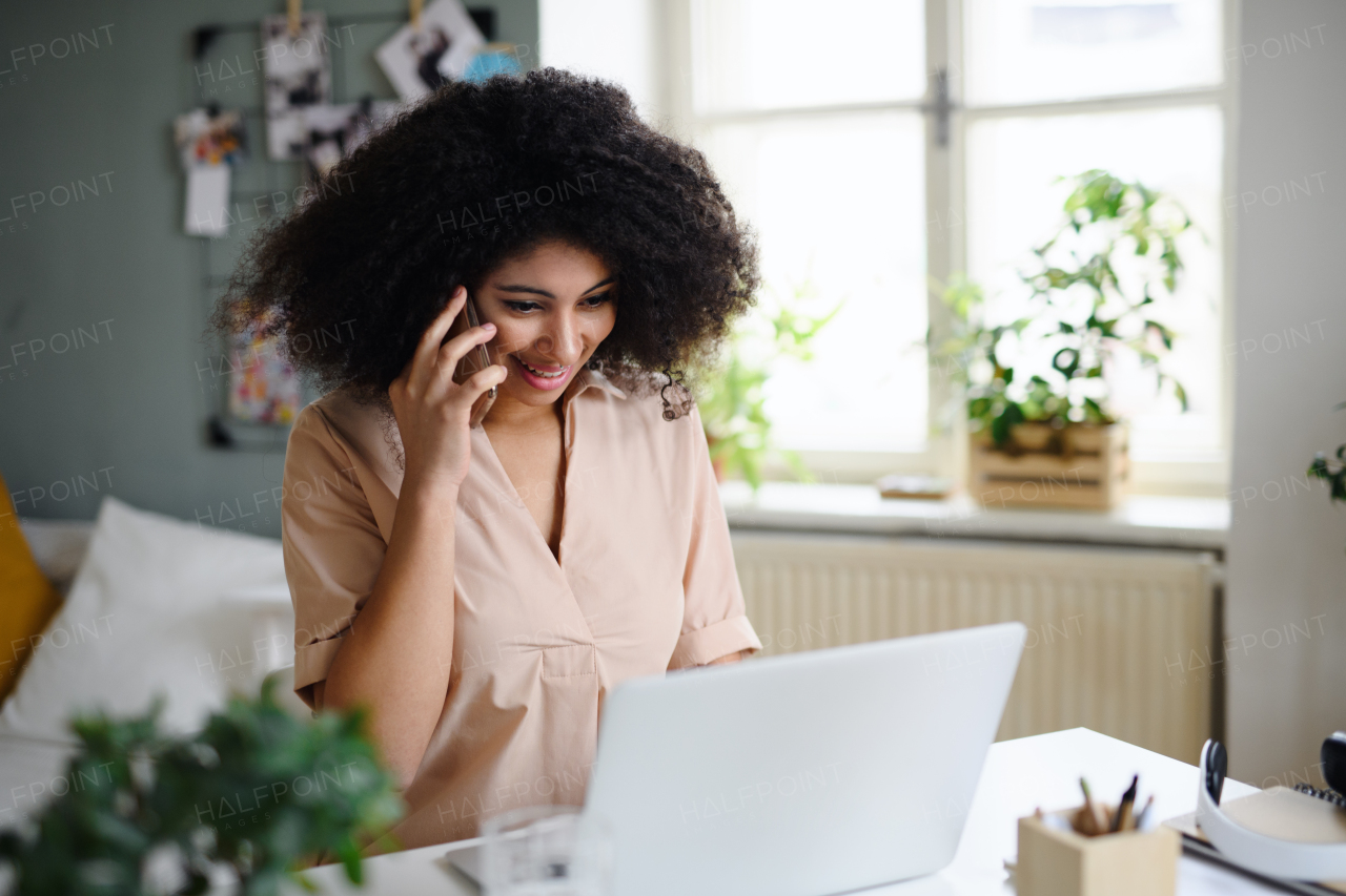 Portrait of young woman with laptop and smartphone indoors at home, home office concept.