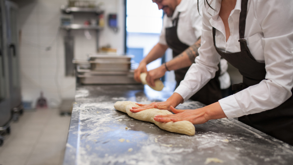 An unrecogniozable chef and cook working on their dishes indoors in restaurant kitchen.