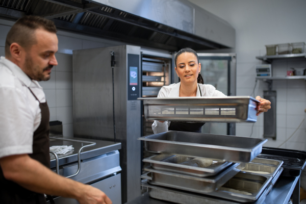 A chef and cook working on their dishes indoors in restaurant kitchen.