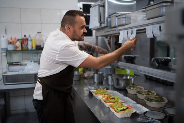 A chef taking order slip in commercial kitchen.