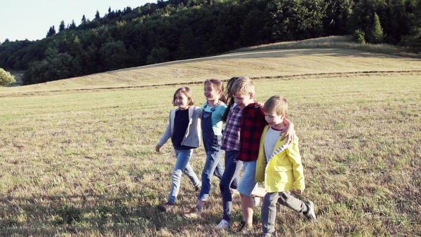 Portrait of group of school children standing on field trip in nature, walking. Slow motion.