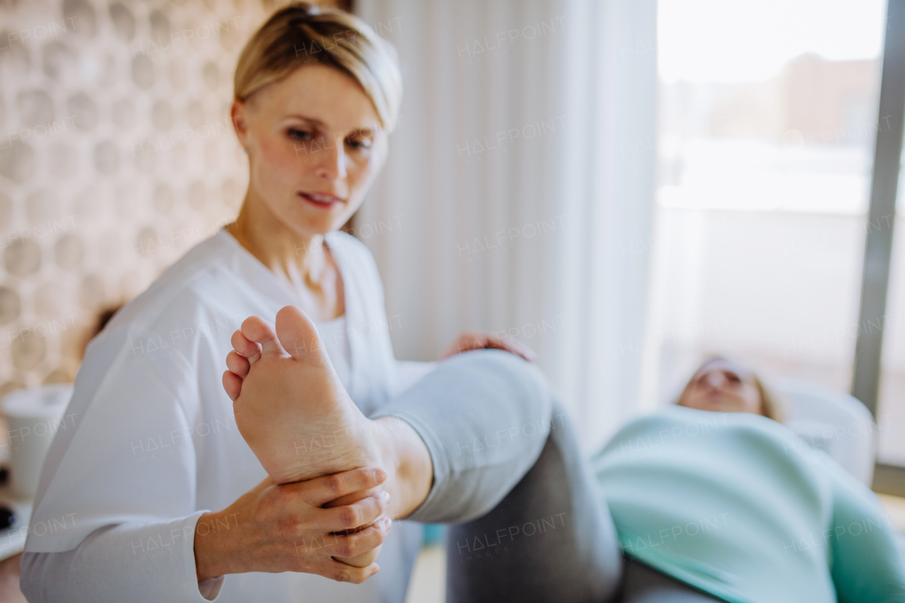 A mid adult physiotherapist woman exercising with overweight woman indoors in rehabilitation center