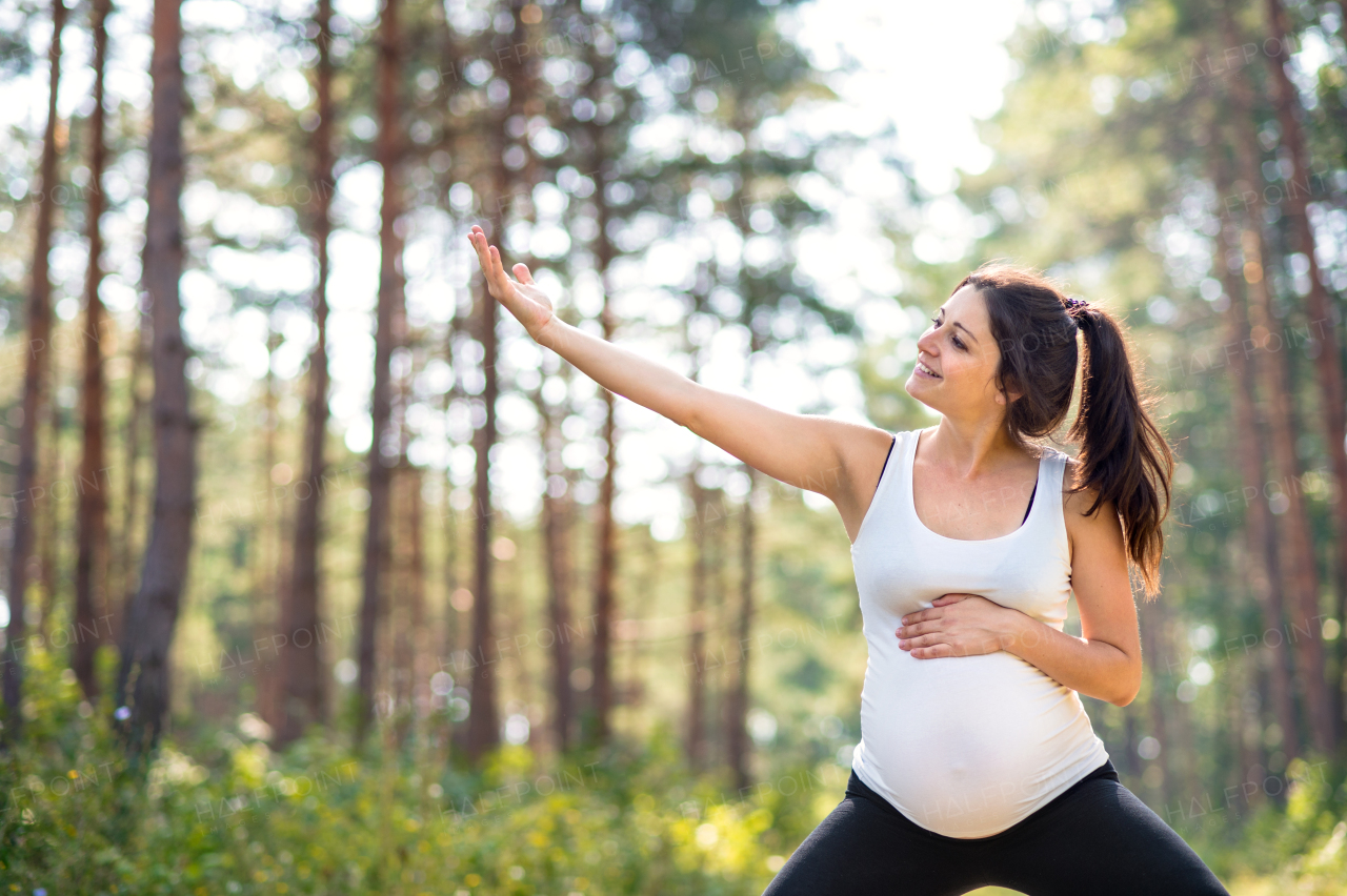 Front view portrait of happy pregnant woman outdoors in nature, doing exercise.