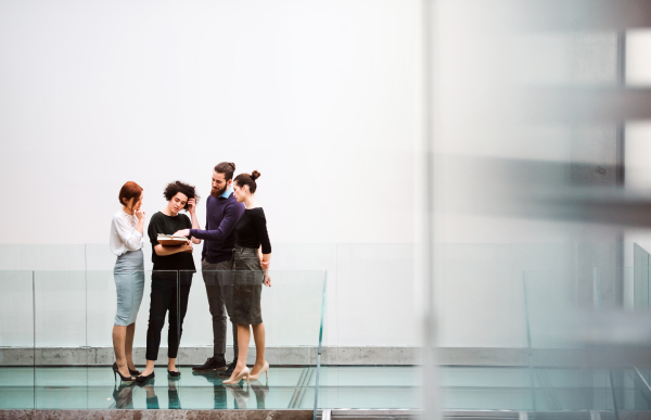 A group of young businesspeople standing near staircase, talking. Copy space.