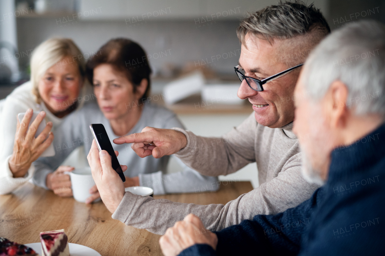 A group of senior friends at home, using smartphones.