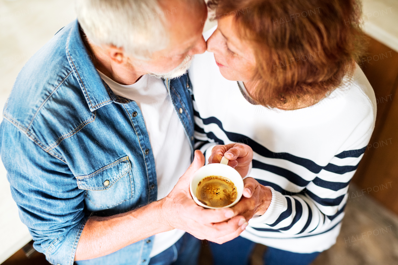 Senior couple at home. An old man and woman inside the house, holding a cup of coffee. Top view.